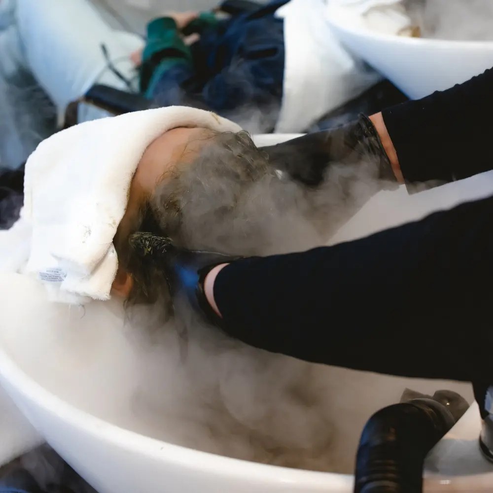 A stylist preparing a repairing hair serum at Hāste Urban Hair Spa