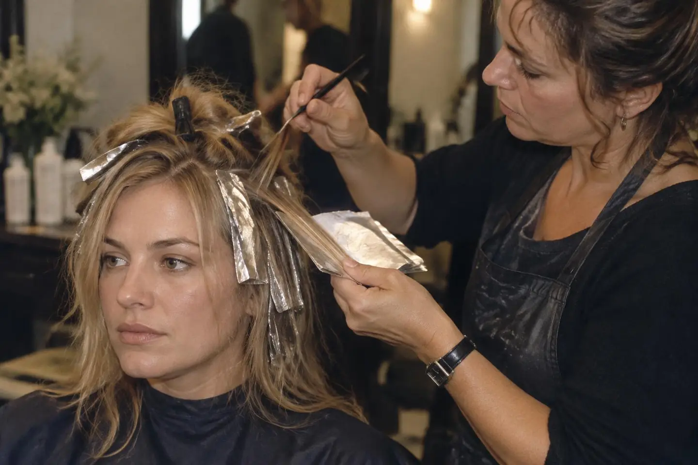 A colourist placing foil highlights in fine sections of a client's blonde hair