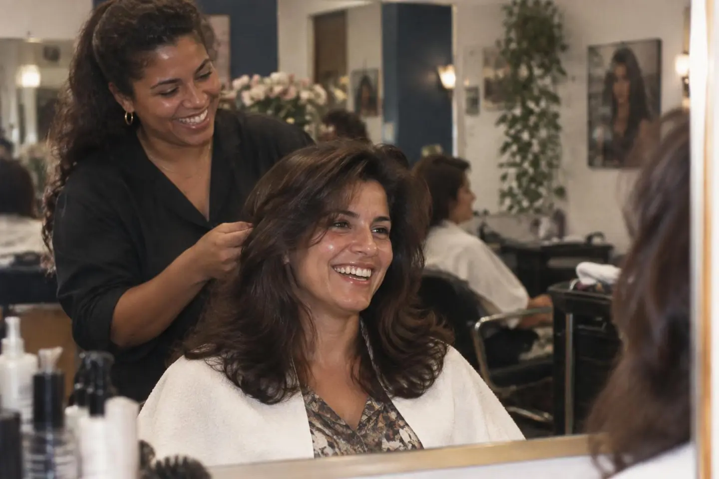 A Brazilian client and her stylist laughing over a smooth blow-dry with natural movement